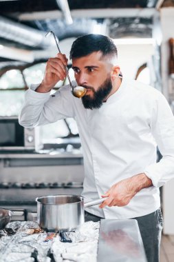 Lezzetli çorba yapıyor. Mutfakta yemek pişiren beyaz üniformalı bir şef. İşte yoğun bir gün..