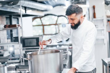 Su kaynatıyor. Mutfakta yemek pişiren beyaz üniformalı bir şef. İşte yoğun bir gün..