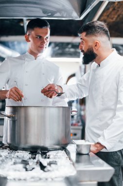 Diğer çalışanların yardımıyla. Mutfakta yemek pişiren beyaz üniformalı bir şef. İşte yoğun bir gün..