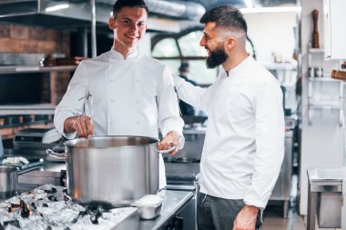 Diğer çalışanların yardımıyla. Mutfakta yemek pişiren beyaz üniformalı bir şef. İşte yoğun bir gün..