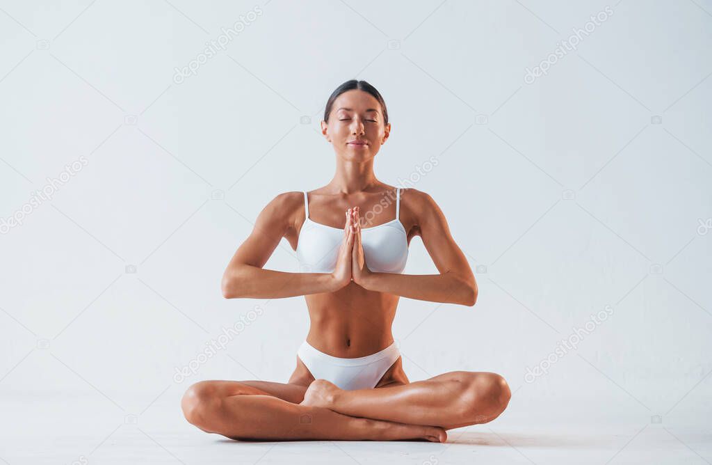 Practicing yoga exercises. Beautiful woman with slim body in underwear is in the studio.