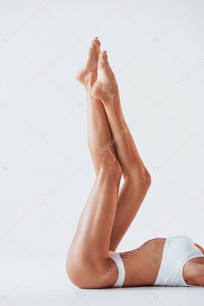 Side view of girl that lying down. Beautiful woman with slim body in underwear is in the studio.