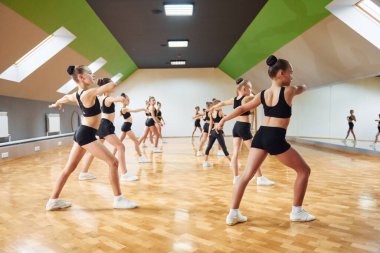 İçeride birlikte atletizm egzersizi yapan bir grup kız çocuğun yan görüntüsü..