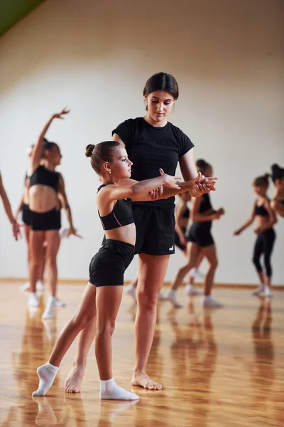 女人教和帮助 一群在室内一起进行体育锻炼的女童 — 图库照片
