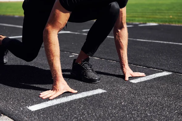 ランナーは軌道上でスタート位置にあります スポーツ若いです男で黒シャツとパンツ屋外で昼間 — ストック写真