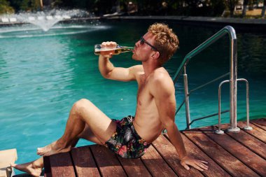 Pozitif genç adam gündüz vakti yüzme havuzunda dinleniyor..