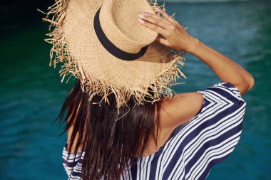 Hasır şapkalı. Kız gündüz vakti havuzda eğlenip dinleniyor. Tatil kavramı.