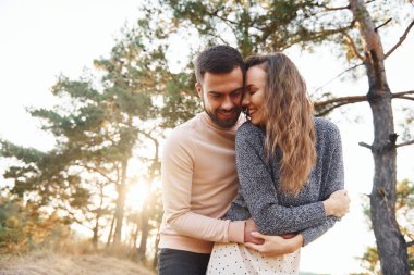 Birbirlerine sarılırlar. Neşeli genç çift dışarıda birlikte dinleniyor..