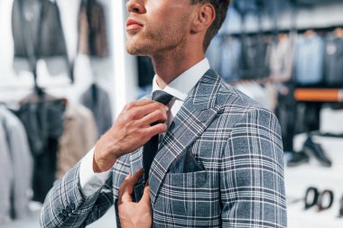 Ceketli, kravatlı. Modern mağazada yeni kıyafetleri olan genç bir adam. Erkekler için pahalı bir elbise..