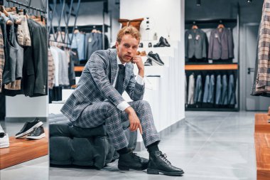 Modern mağazada yeni kıyafetleri olan genç bir adam. Erkekler için pahalı bir elbise..