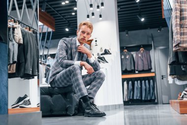 Modern mağazada yeni kıyafetleri olan genç bir adam. Erkekler için pahalı bir elbise..