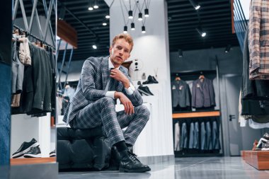 Modern mağazada yeni kıyafetleri olan genç bir adam. Erkekler için pahalı bir elbise..