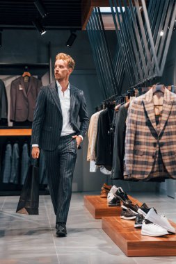 Alışveriş günü. Modern mağazada yeni kıyafetleri olan genç bir adam. Erkekler için pahalı bir elbise..