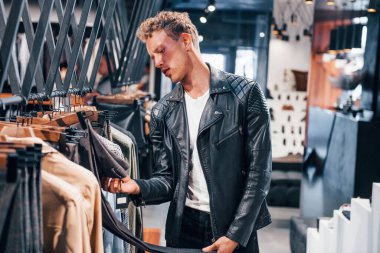 Kaliteli ürünler. Modern mağazada yeni kıyafetleri olan genç bir adam. Erkekler için pahalı bir elbise..