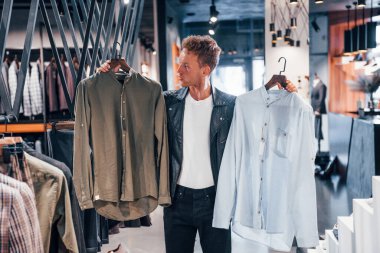 Kaliteli ürünler. Modern mağazada yeni kıyafetleri olan genç bir adam. Erkekler için pahalı bir elbise..