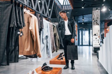 Büyük seçim. Modern mağazada yeni kıyafetleri olan genç bir adam. Erkekler için pahalı bir elbise..