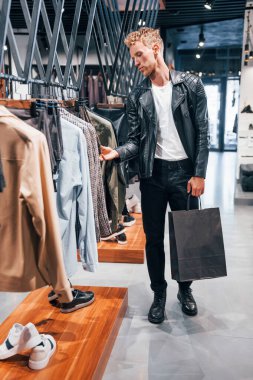 Hafta sonu alışverişi. Modern mağazada yeni kıyafetleri olan genç bir adam. Erkekler için pahalı bir elbise..