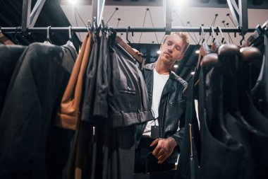 Hafta sonu alışverişi. Modern mağazada yeni kıyafetleri olan genç bir adam. Erkekler için pahalı bir elbise..