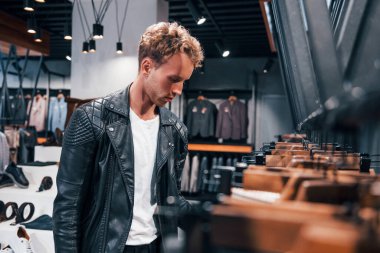 Hafta sonu alışverişi. Modern mağazada yeni kıyafetleri olan genç bir adam. Erkekler için pahalı bir elbise..