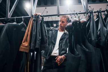 Hafta sonu alışverişi. Modern mağazada yeni kıyafetleri olan genç bir adam. Erkekler için pahalı bir elbise..