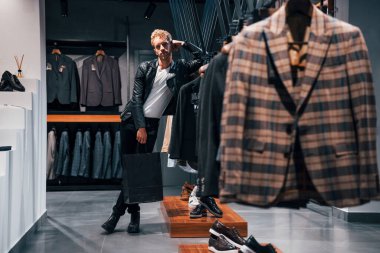 Hafta sonu alışverişi. Modern mağazada yeni kıyafetleri olan genç bir adam. Erkekler için pahalı bir elbise..