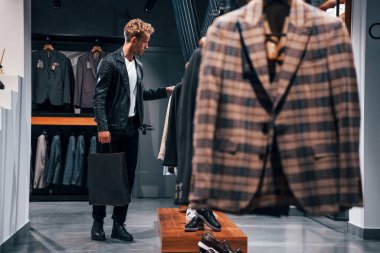 Hafta sonu alışverişi. Modern mağazada yeni kıyafetleri olan genç bir adam. Erkekler için pahalı bir elbise..