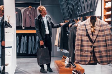 Güzel siyah ceketli. Modern mağazada yeni kıyafetleri olan genç bir adam. Erkekler için pahalı bir elbise..