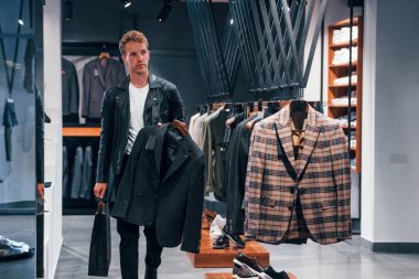 Tercih yapıldı. Modern mağazada yeni kıyafetleri olan genç bir adam. Erkekler için pahalı bir elbise..