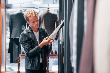 Güzel siyah ceketli. Modern mağazada yeni kıyafetleri olan genç bir adam. Erkekler için pahalı bir elbise..
