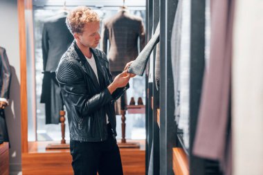 Güzel siyah ceketli. Modern mağazada yeni kıyafetleri olan genç bir adam. Erkekler için pahalı bir elbise..