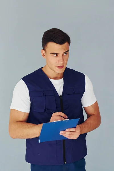 Schreibt Notizblock Männlicher Arbeiter Blauer Uniform Steht Atelier Vor Weißem — Stockfoto