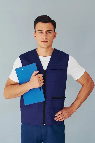 Hält Notizblock Männlicher Arbeiter Blauer Uniform Steht Atelier Vor Weißem — Stockfoto
