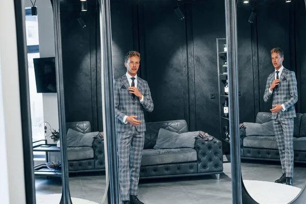 Aynaya bakıyor. Modern mağazada yeni kıyafetleri olan genç bir adam. Erkekler için pahalı bir elbise..