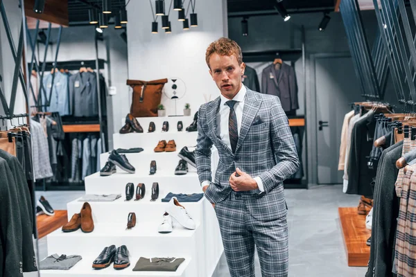 Ceketli, kravatlı. Modern mağazada yeni kıyafetleri olan genç bir adam. Erkekler için pahalı bir elbise..