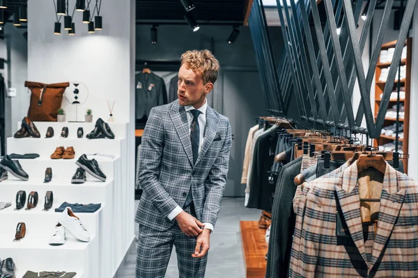 Ceketli, kravatlı. Modern mağazada yeni kıyafetleri olan genç bir adam. Erkekler için pahalı bir elbise..