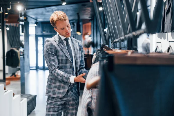 Modern mağazada yeni kıyafetleri olan genç bir adam. Erkekler için pahalı bir elbise..