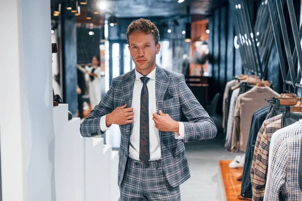 Giyinmeyi deniyor. Modern mağazada yeni kıyafetleri olan genç bir adam. Erkekler için pahalı bir elbise..
