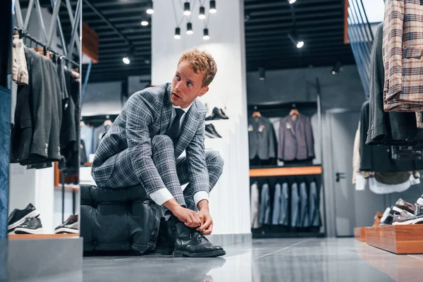 Modern mağazada yeni kıyafetleri olan genç bir adam. Erkekler için pahalı bir elbise..