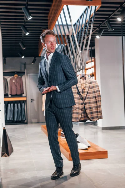 Alışveriş günü. Modern mağazada yeni kıyafetleri olan genç bir adam. Erkekler için pahalı bir elbise..