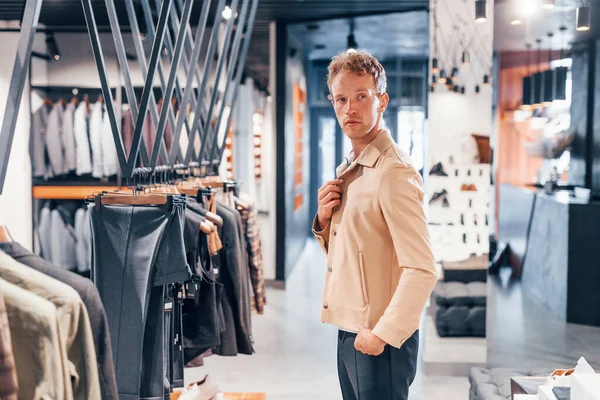 Kaliteli ürünler. Modern mağazada yeni kıyafetleri olan genç bir adam. Erkekler için pahalı bir elbise..
