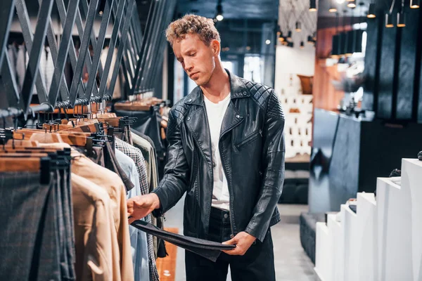 Kaliteli ürünler. Modern mağazada yeni kıyafetleri olan genç bir adam. Erkekler için pahalı bir elbise..