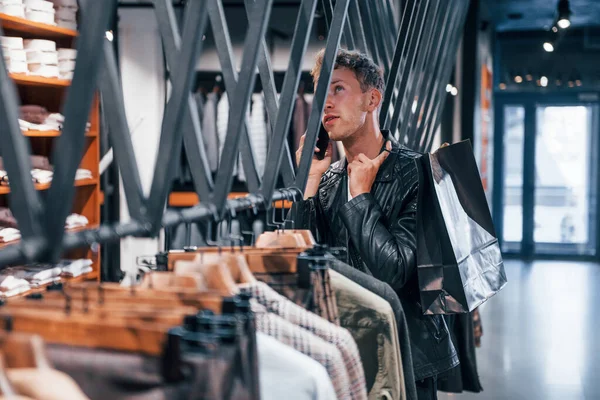 Parle Téléphone Jeune Homme Dans Magasin Moderne Avec Nouveaux Vêtements — Photo