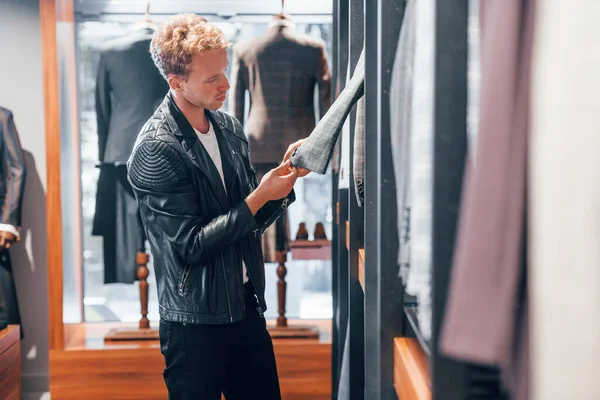 Güzel siyah ceketli. Modern mağazada yeni kıyafetleri olan genç bir adam. Erkekler için pahalı bir elbise..