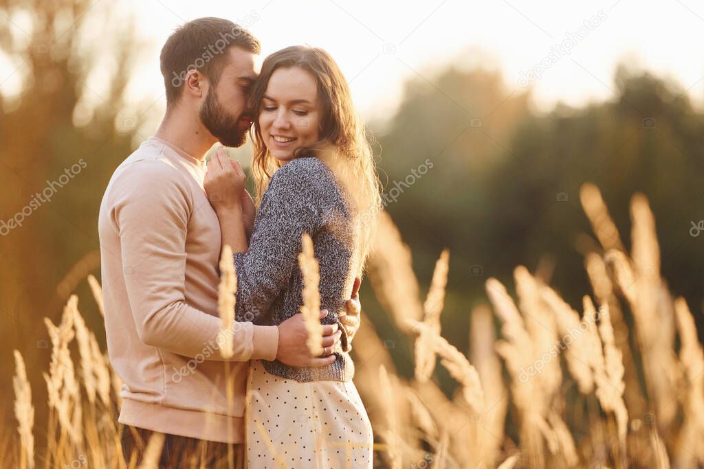 Beautiful agricultural field. Cheerful lovely young couple having a rest outdoors together.