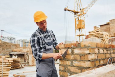 İnşaat için spatulayla birlikte. Üniformalı ve güvenlik ekipmanlı işçilerin inşaat işi var.