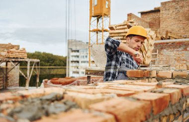 İnşaat için spatulayla birlikte. Üniformalı ve güvenlik ekipmanlı işçilerin inşaat işi var.