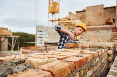 Üniformalı inşaat işçisi ve güvenlik ekipmanı inşaatında çalışıyor.