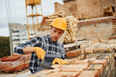 Üniformalı inşaat işçisi ve güvenlik ekipmanı inşaatında çalışıyor.