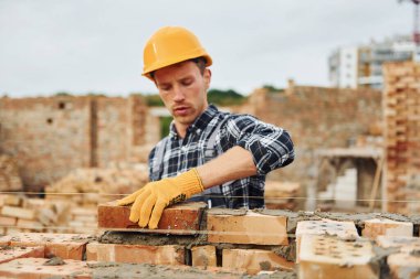 Tuğla döşemek. Üniformalı inşaat işçisi ve güvenlik ekipmanı inşaatında çalışıyor.