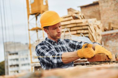 Tuğla döşemek. Üniformalı inşaat işçisi ve güvenlik ekipmanı inşaatında çalışıyor.